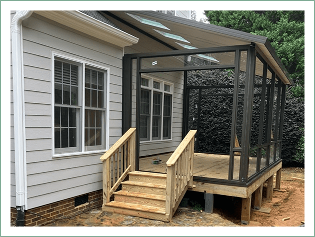 A wooden porch with stairs and a black screened enclosure.