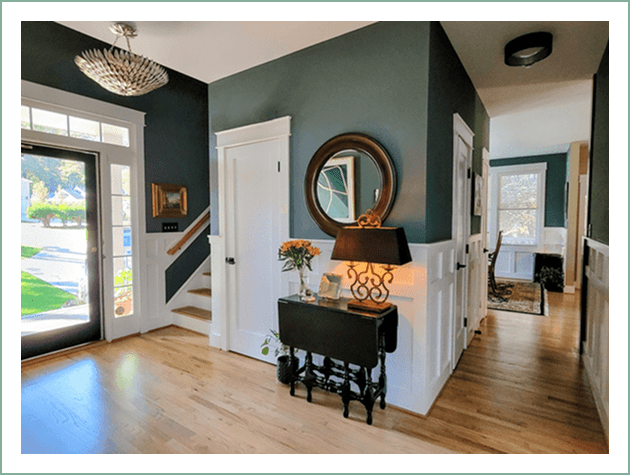 Cozy entryway with a staircase, mirror, and a piano bench.